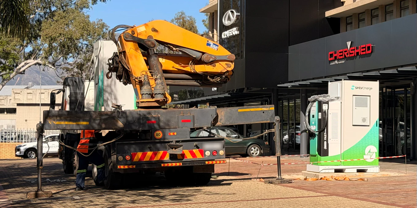 Installing the SAEV Charge station at RIVO Quarters, Paarl: a crane truck beside the charger and battery cabinet, in front of the Chery dealership